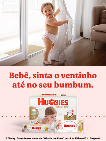 Bebê de fralda roupinha Huggies em pé rindo